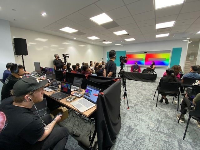 Photo of a conference with a couple of camera and film crews
