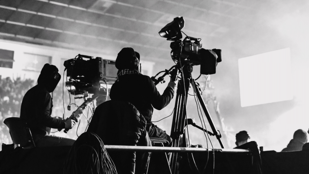 Two cameraman filming an event. Picture is in black and white.