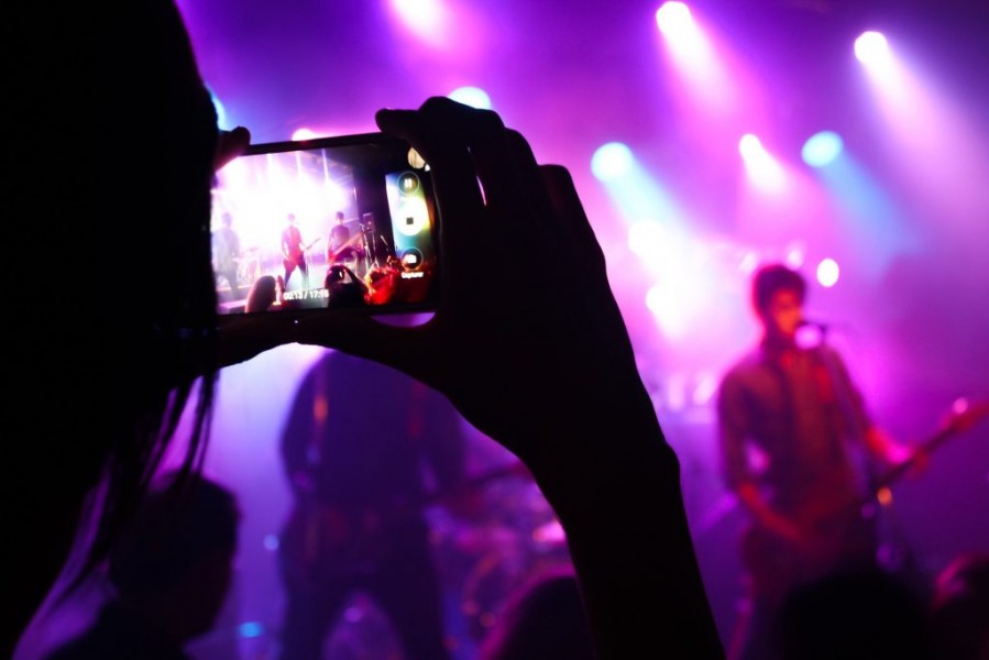 Someone holding a smartphone filming a live band.